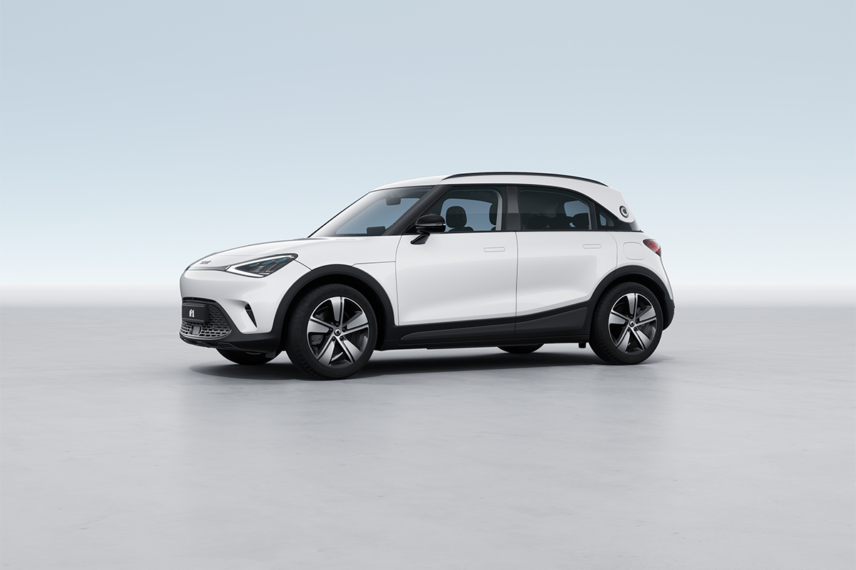 Das Bild zeigt ein weißes, kompaktes Fahrzeug, das schräg von vorne links zu sehen ist. Das Auto steht auf einer hellen, ebenen Fläche, vor einem gleichmäßig hellblauen Hintergrund ohne erkennbare Umgebung oder weitere Objekte.